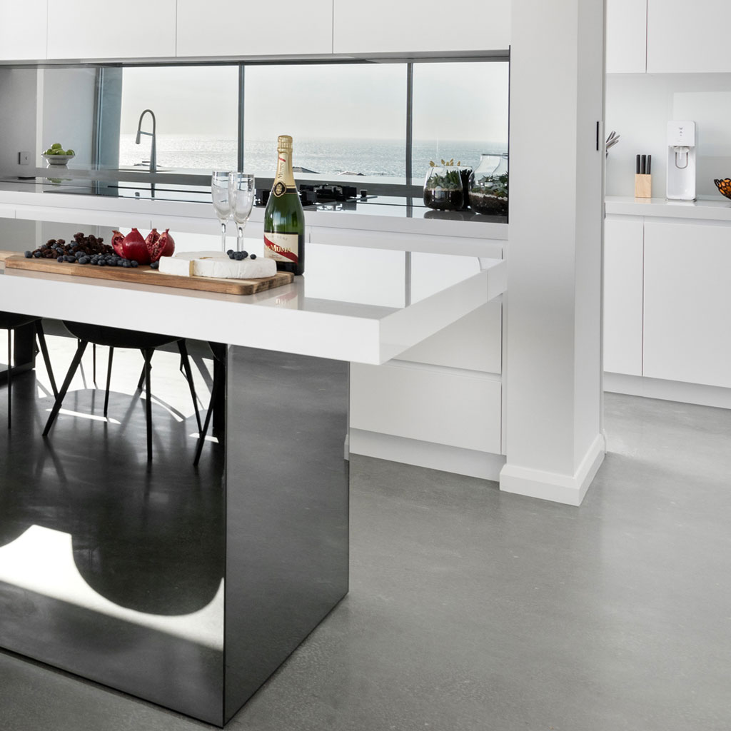 A bottle of wine and a fruit and cheese board placed on a polished concrete tabletop
