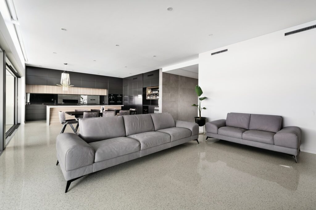 Grey sofas in an open plan living area with a white polished concrete floor