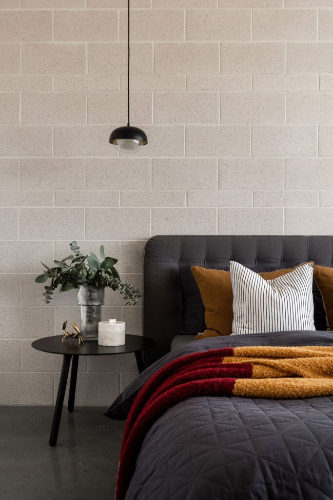 Queen bed with black covers on a black polished concrete floor